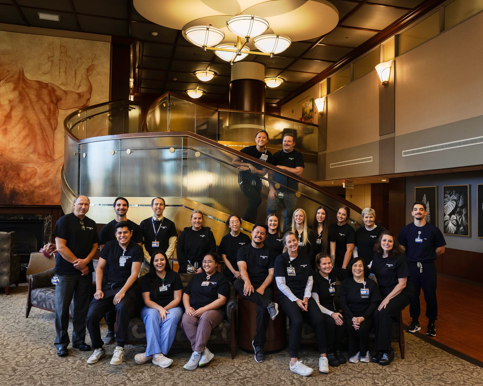 A large team in matching black shirts arranged on a staircase in a hotel lobby