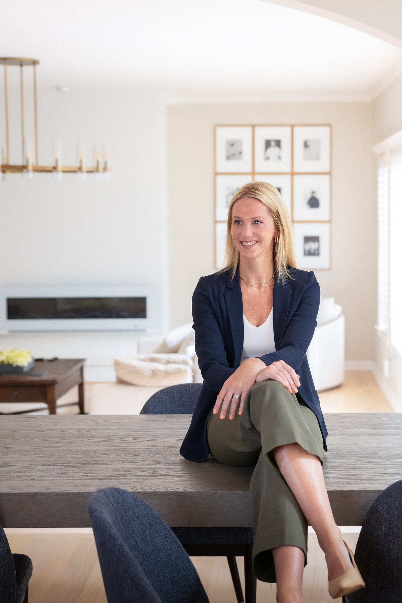Founder in a navy blazer seated on the edge of a dining table in a bright room