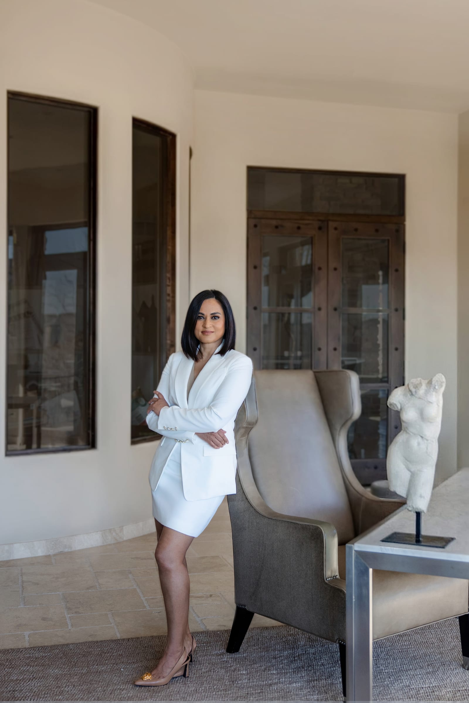 Business owner in a white coat standing beside a sculpture in a pale designed room