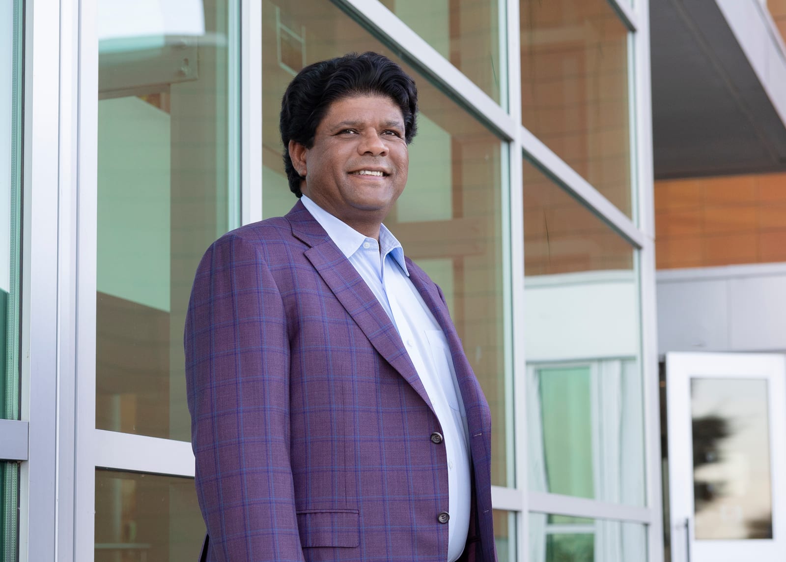 Executive in a lilac checked blazer standing beside a bright window