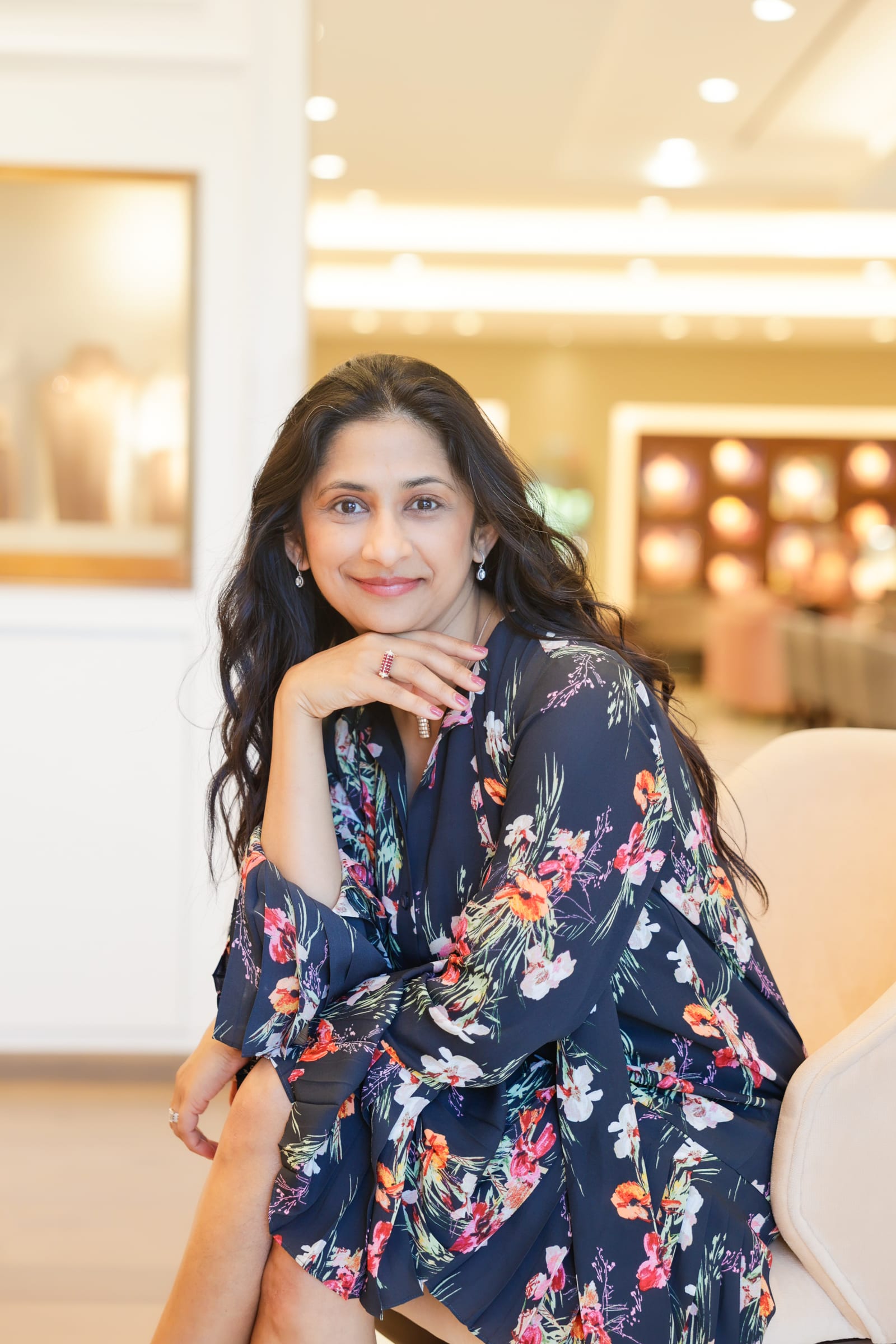 Business owner in a floral dress seated in a bright, softly lit reception area