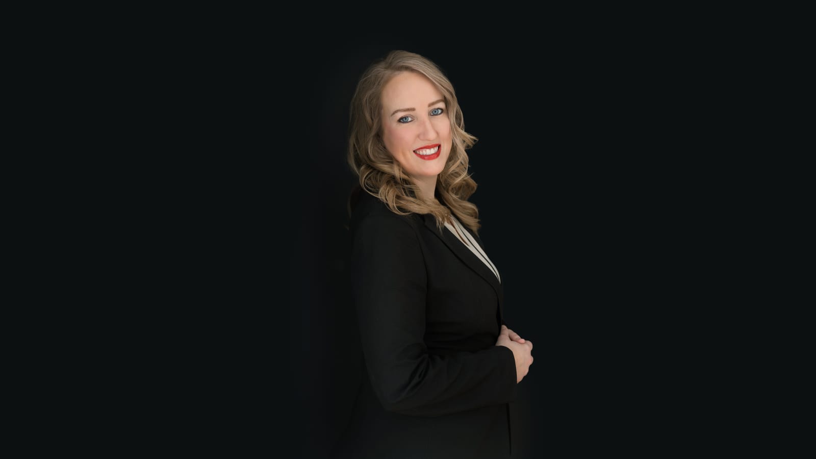 Professional in black standing against a deep dark ground