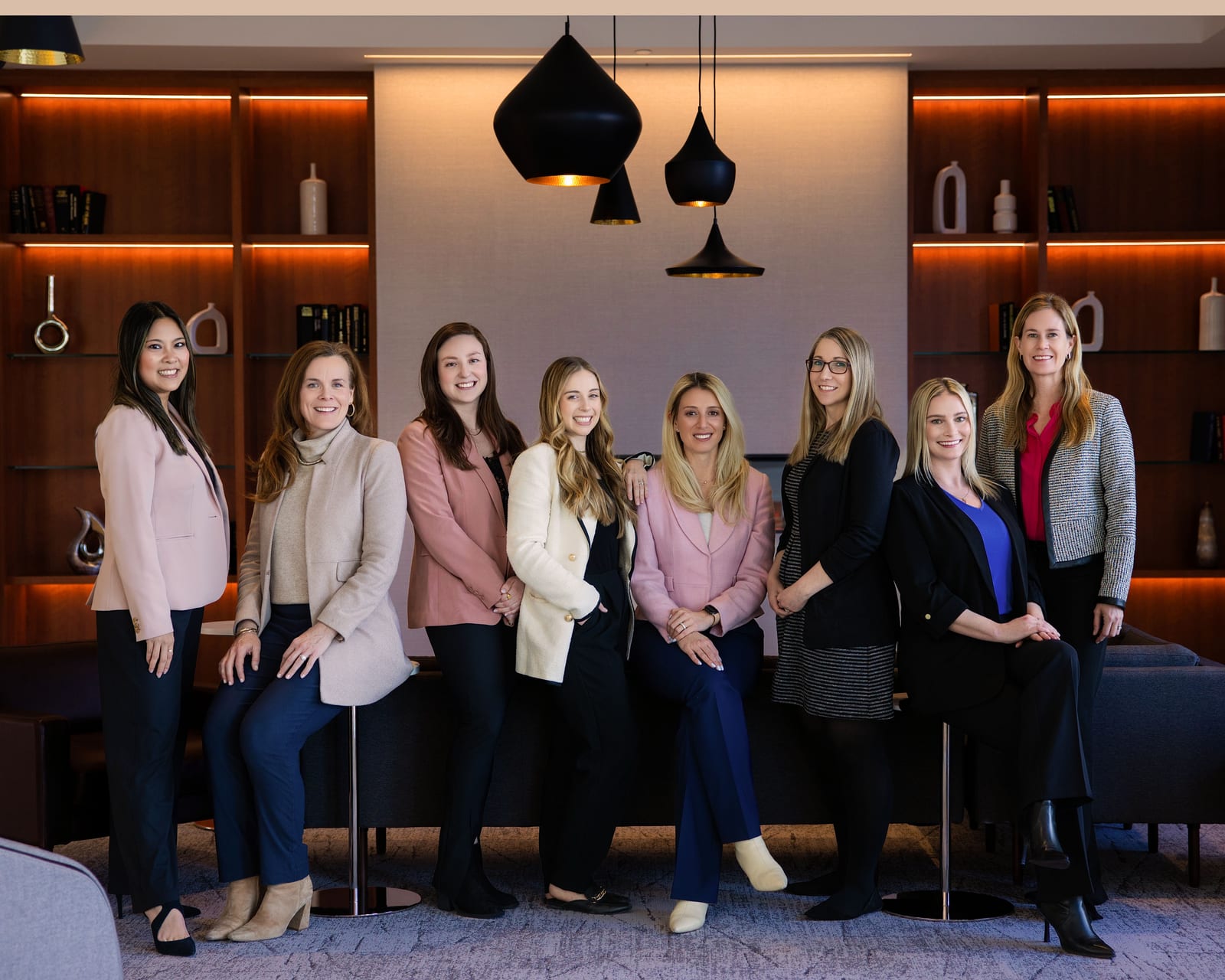 A team of nine standing together in a warmly lit showroom with pendant lights