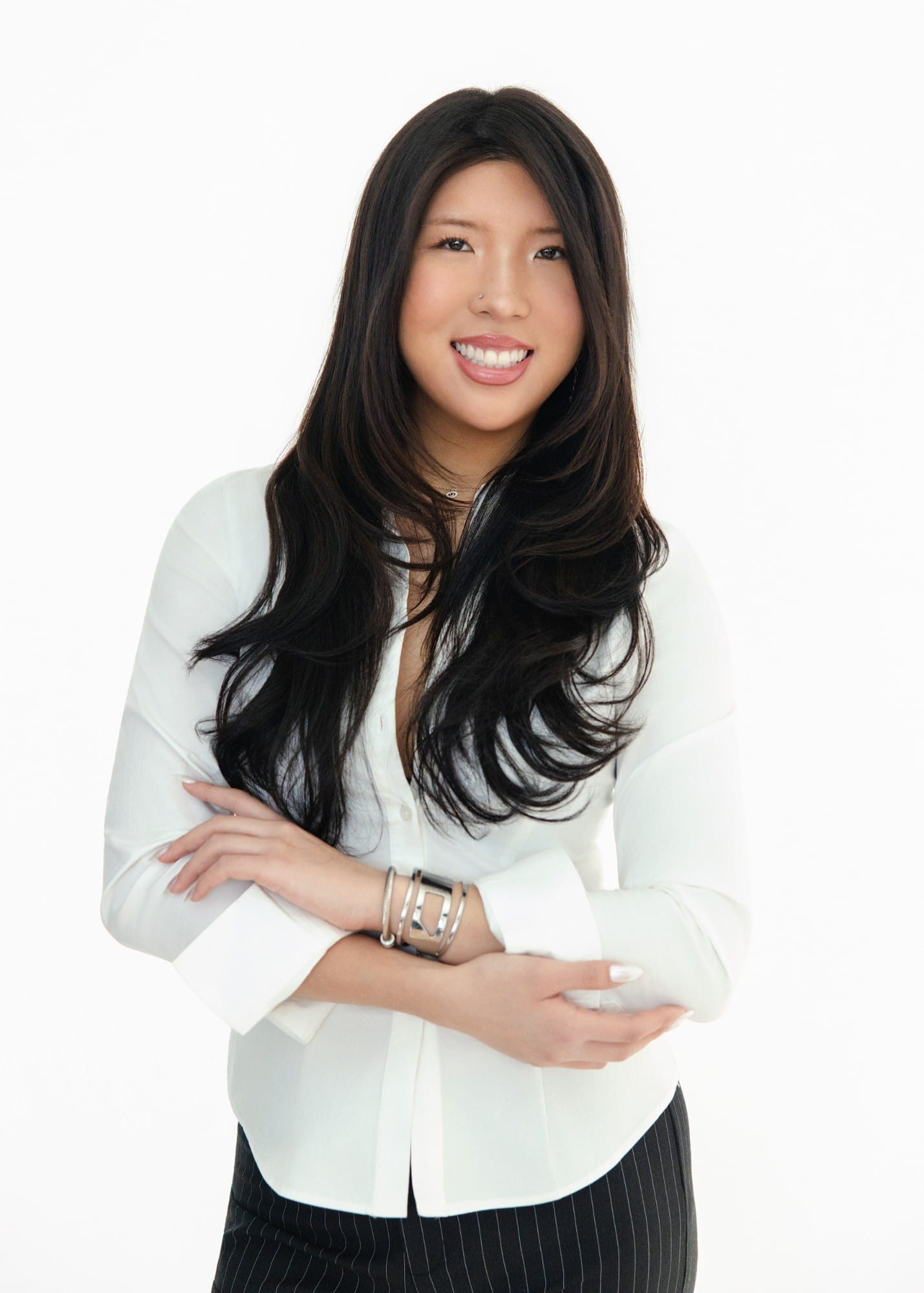 Professional in a white shirt with arms folded, against a white ground