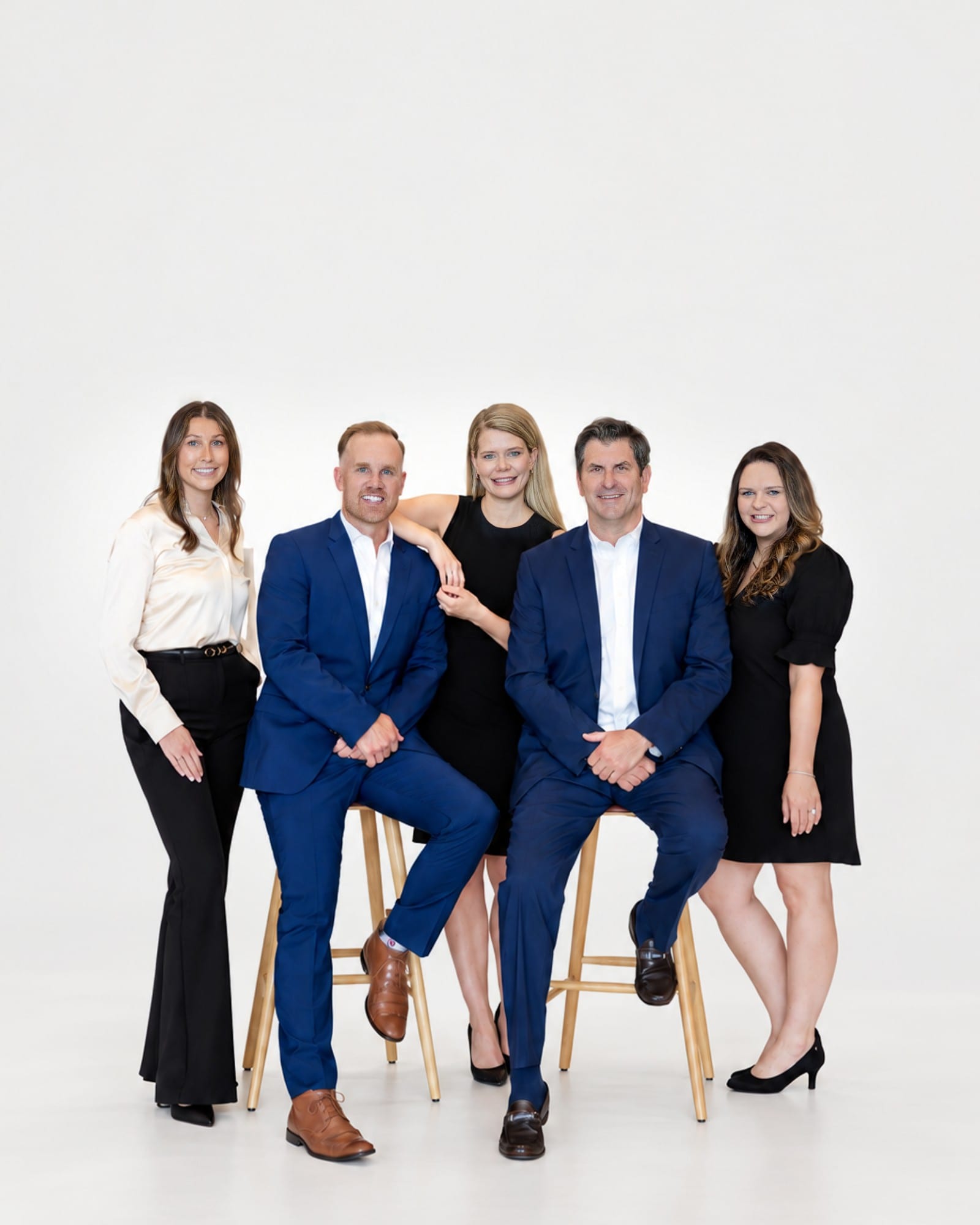 A team of five photographed together on stools against a plain white studio ground